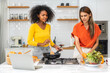 Diversity young happy love LGBT, LGBTQ caucasian and african family lesbian couple woman cook vegan food healthy eat with fresh vegetable salad in kitchen at home, pride, rainbow.Lgbt lesbian couple