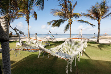 Two enpty hammock between coconut palm tree in fron of the beach. Concept of summer vacation near the sea. Holisays on bali island