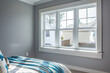 Bedroom view from a sunny window seat, featuring soft gray walls and vibrant blue.