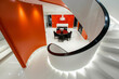 Looking down a spiral staircase at a glossy white entryway with an orange wall.