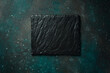 Square slate black plate. On a dark green-turquoise background. Free space for text.