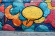 Speech and thought bubbles in a colorful graffiti style adorn a flat concrete wall.