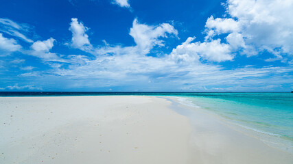 Wall Mural - A pristine white sand beach in the Maldives, meeting turquoise blue waters under a partly cloudy, sunny sky. The tranquil scene captures the essence of a perfect tropical paradise.