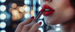 A closeup of the hand applying lipstick in front of mirror,