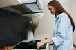 © SHOTPRIME STUDIO - Woman in blue shirt cooking eggs on electric stove in kitchen, culinary concept