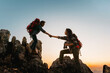  man and a woman are helping each other climb a mountain