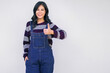 woman in blue overalls is giving a thumbs up