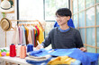 Trainee asian teenage man fashion designer  vocation and  education work on designer in the showroom,  Lifestyle Stylish tailor clothing design and cutting cloths in studio.  Education Concept