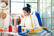 Asian young women fashion designer  working on her designer in the showroom,  Lifestyle Stylish tailor clothing design and cutting cloths in studio.  Business small Concept
