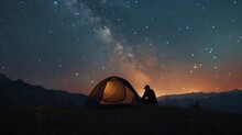 A Man Setting Up A Tent Under A Starry Sky In The Wilderness.