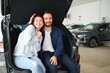 © Serhii - First big buy together. Portrait of a happy young couple hugging in a car salon