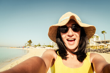 Happy brunette woman tourist excited take selfie pose at beach on vacation show peace fingers symbol - Millennial girl having fun smiling at camera - People and holidays concept