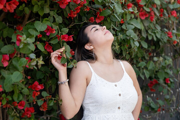 beautiful young woman wearing white summer dress surrounded by bougainvilia flowers