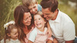 © Pavel Lysenko - A heartwarming photo captures a happy family, consisting of a mother, father, and two children, smiling warmly at the camera, radiating love and joy in their togetherness