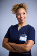 Studio Portrait Of Smiling Female Nurse Wearing Uniform With Digital Tablet Against Grey Background