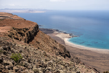 Wall Mural - Views of Caleta de Famara from the viewpoint of El Rio. Turquoise ocean. Blue sky with big white clouds. Caleta de Sebo. Village. Volcanoes. Lanzarote, Canary Islands, Spain