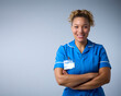 Studio Portrait Of Smiling Female Nurse Wearing Uniform With Digital Tablet Against Grey Background