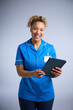 Studio Portrait Of Smiling Female Nurse Wearing Uniform With Digital Tablet