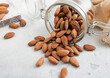 Raw healthy organic almond nuts snack in glass jar on white kitchen table.Macro.