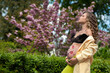 pregnant curly young girl near trees, cherry blossoms, belly with floral ornament, dreamy, at peace
