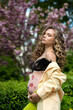 pregnant curly young girl near trees, cherry blossoms, belly with floral ornament