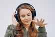 Woman, studio or dancing with headphones and hand for subscription, streaming or music with happiness. Female student or celebrate on backdrop with audio for podcast, happy with sound in California