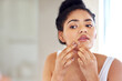 Skincare, face and woman popping pimple in mirror with mockup, dirt or scar on skin in home. Dermatology, facial wellness and girl in bathroom to squeeze acne, checking reflection or morning routine