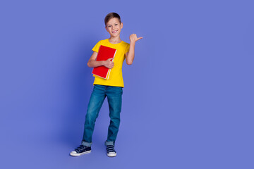 Wall Mural - Photo of cute clever smart boy dressed stylish clothes showing empty space bookshop isolated on violet color background