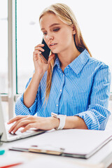 Wall Mural - Concentrated female manager having mobile phone conversation about business checking report on netbook, employee checking banking account contact service operator and browsing web page on laptop