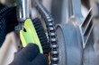 Male hands in gloves cleaning the chain of motorcycle, close up. Motorcycle maintenance, care of the vehicle concepts