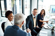 © peopleimages.com - Business people, meeting or office with tech and shaking hands for deal, thank you for global sales. Group, workplace or handshake with monitor and paperwork for international, b2b or collaboration