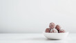 Energy balls in white plate on white background. Healthy raw sweet dessert vegetarian candies made of dates, cocoa powder and coconut. Healthy food concept.