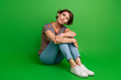 Full body portrait of minded doubtful lady sit floor look empty space ponder hesitate isolated on green color background