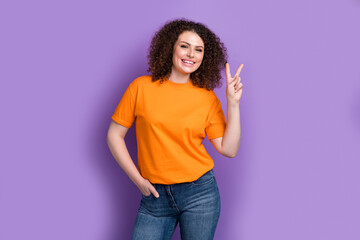 Wall Mural - Photo of excited funky lady dressed orange t-shirt smiling showing v-sign isolated violet color background