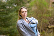 Upper body portrait of a happy woman looking to camera while holding and carrying it in a baby carrier