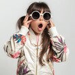 Photo of a schoolgirl girl with her mouth open in surprise, wearing glasses and fashionable clothing. A attention-grabbing surprised, shocked little fashionista.