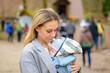 Portrait of a happy woman looking to her baby while holding and carrying it in a baby carrier