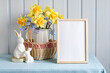 Easter mockup with an empty frame, a bouquet of garden daffodils and figures of Easter bunnies. spring background.
