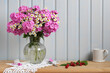 still life with garden phlox and daisies in a jug, raspberries on the table. summer composition. cottage.