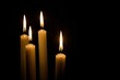 Photo of burning mourning candles on a table against a black background. Lighting candles for bad events, tragedies, in memory, memorial candles, reverence, rest in peace.