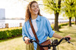 © maxbelchenko - Young smiling woman riding bicycle bike on sidewalk in city spring park outdoors. Active urban healthy lifestyle concept.