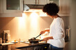 © peopleimages.com - Black woman, pan and cooking on stove in home, frying and meal preparation in kitchen. Female person, apartment and nutrition in food, diet and wellness for cuisine on gas for dinner routine in house