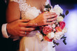 Hands of bride and groom with rings on wedding bouquet. Marriage concept.