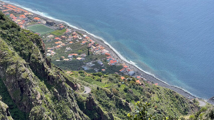 Wall Mural - Aerial view of a coastal village on Madeira Island, nestled between steep cliffs and the blue Atlantic Ocean