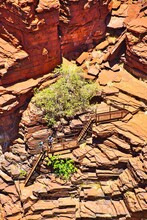 Two Unrecognizable People Descending The Steep Stairs Over Red Rocks Into The Deep Joffre Gorge, In The Remote Karijini National Park, Western Australia.
