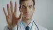 © JovialFox - Young non binary man wearing doctor uniform and stethoscope doing stop sing with palm of the hand. warning expression with negative and serious gesture on the face.