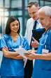 © peopleimages.com - Doctor, group and hospital teamwork with tablet for research or telehealth communication, online or consultation. Men, woman and medical app for client conversation or internet, website or insurance