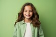 © MediaRaw - A young girl with long brown hair is smiling and wearing a green shirt