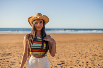 Multicultural Latina girl posing on the beach with a hat on a sunny summer day