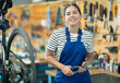 Young woman bicycle repair service worker in uniform posing with tool